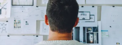 photo of a man staring at papers hanging on the wall